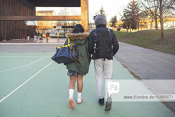 Rear view of young couple walking on sports field