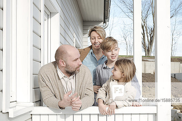Glückliche Familie spricht auf der Veranda ihres Hauses
