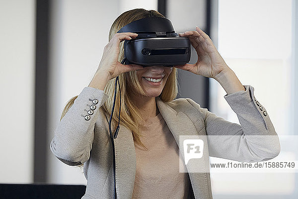 Smiling businesswoman wearing VR glasses in office