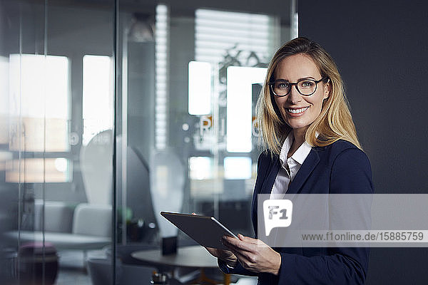 Porträt einer lächelnden Geschäftsfrau  die ein Tablett im Amt hält