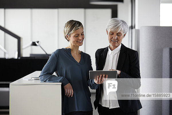 Zwei Geschäftsfrauen teilen sich das Tablett im Büro