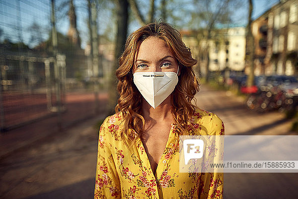 Rothaarige Frau mit einer FFP2-Gesichtsmaske in der Stadt