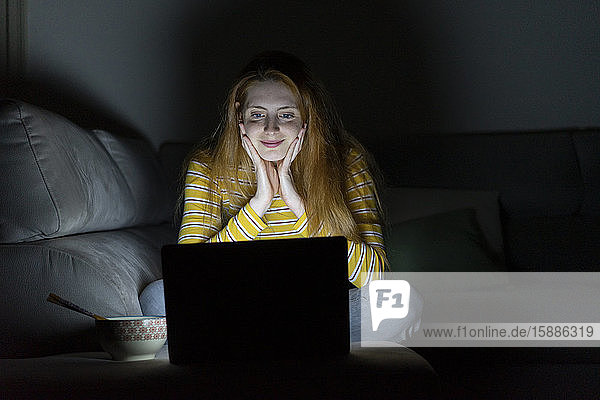 Junge Frau mit einer Laptop-Videokonferenz auf der Couch zu Hause