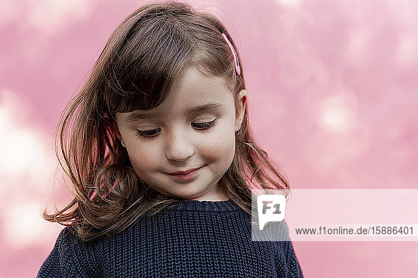 Portrait of smiling little girl in front of pink background