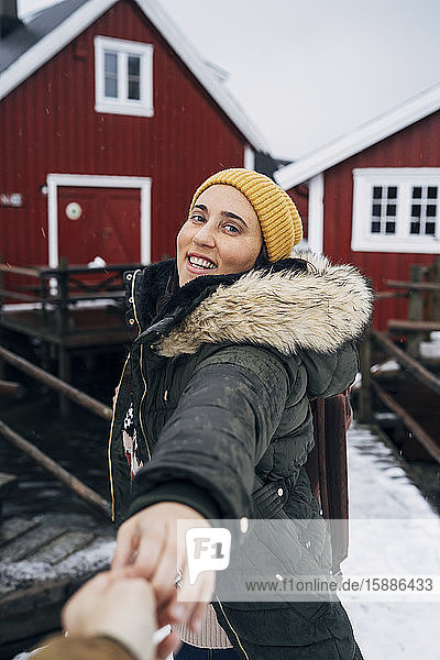 Porträt eines lächelnden Touristen  der die Hand eines Mannes an einer Hütte hält  Lofoten  Norwegen