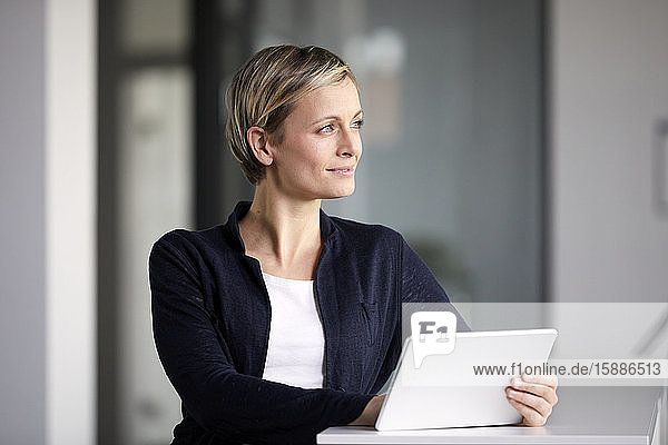 Lächelnde Geschäftsfrau benutzt Tablett im Büro