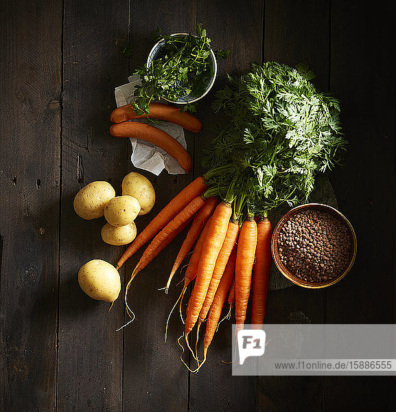 Ein Bündel Karotten  Würste  Petersilie  Kartoffeln und eine Schüssel Linsen