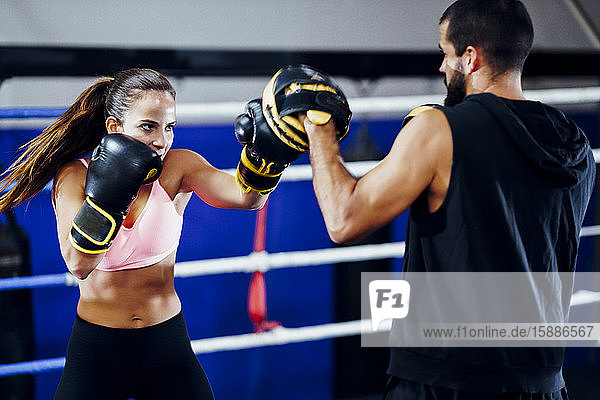 Boxerin beim Sparring mit ihrem Trainer im Fitnessstudio