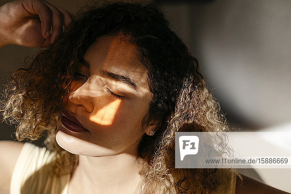 Porträt einer attraktiven jungen Frau mit geschlossenen Augen im Sonnenlicht