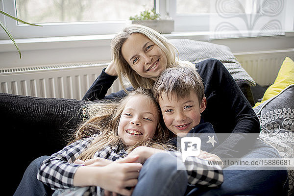 Porträt einer glücklichen Mutter mit Kindern  die sich zu Hause auf der Couch entspannen