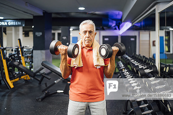 Portrait of senior man lifting dumbbells in gym