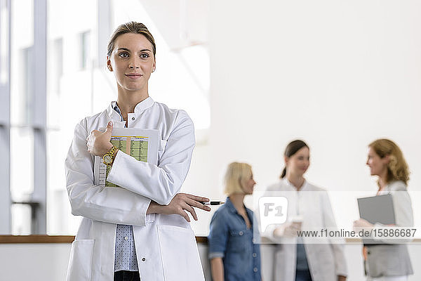 Porträt einer Ärztin im Krankenhaus mit Kollegen im Hintergrund