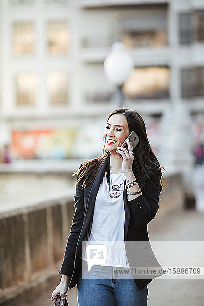 Porträt einer glücklichen Frau am Telefon beim Spaziergang in der Stadt