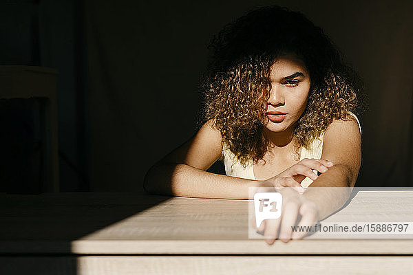 Porträt einer attraktiven jungen Frau  die sich im Sonnenlicht auf einen Tisch lehnt