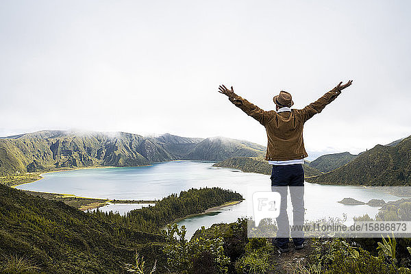 Rear view of explorer with arms raised enjoying view at scenic Sao Miguel Island in Azores Portugal