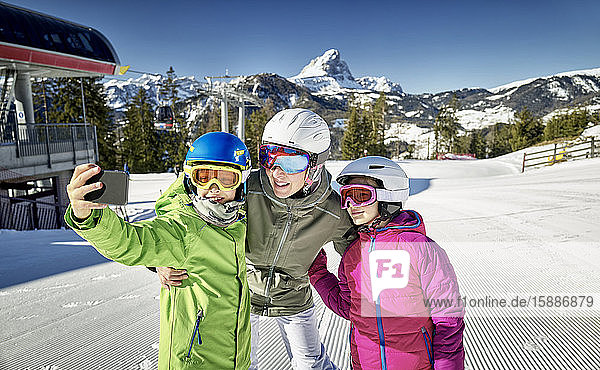 Mutter mit ihren Kindern  die einen Selfie auf der Skipiste machen
