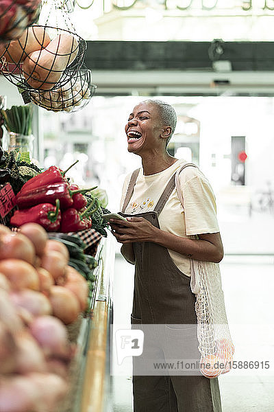 Lachende Frau kauft Lebensmittel in einer Markthalle