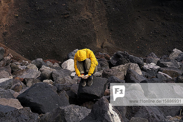 Mann kauert inmitten von Vulkangestein  Insel Sao Miguel  Azoren  Portugal