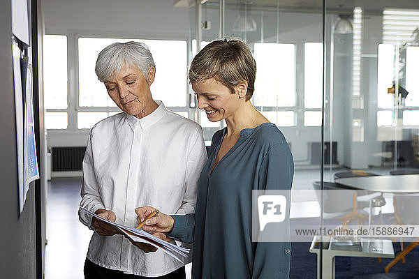 Zwei Geschäftsfrauen arbeiten zusammen auf Papier im Amt