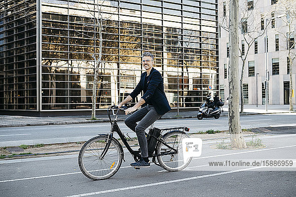 Gray-haired businessman riding on an electric bike through the city center
