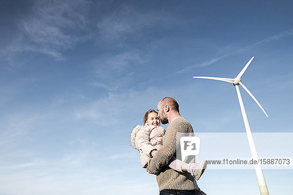 Mature man with his little daughter against sky