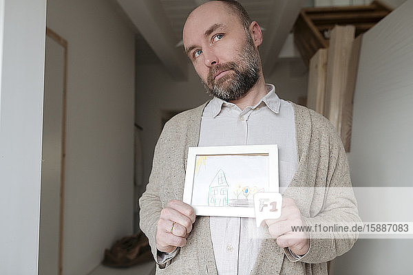 Mature man showing child's drawing at home