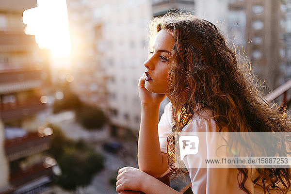 Porträt einer schönen jungen Frau auf dem Balkon bei Sonnenuntergang