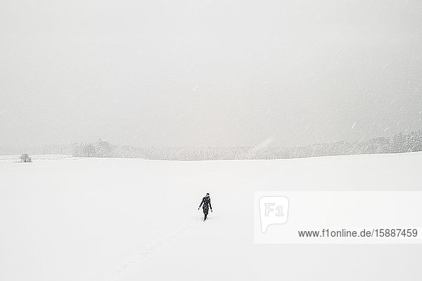 Frau geht allein in schneebedeckter Landschaft