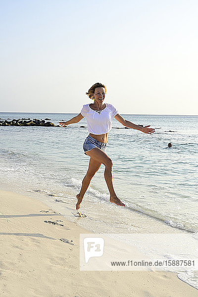 Beautiful woman running and jumping for joy on the beach