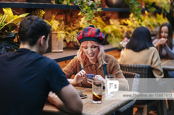 Man and woman having drinks in a restaurant  using smartphone