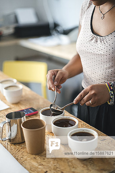Nahaufnahme einer Frau  die in einer Kaffeerösterei arbeitet und Kaffee zubereitet