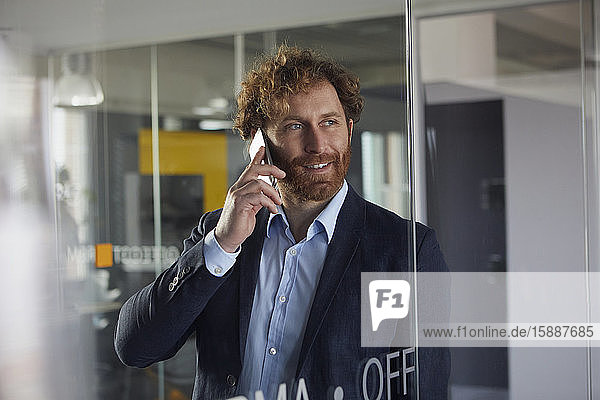 Porträt eines lächelnden Geschäftsmannes im Büro am Telefon