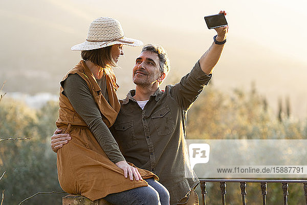 Couple taking selfie with smartphone during the sunset in the countryside