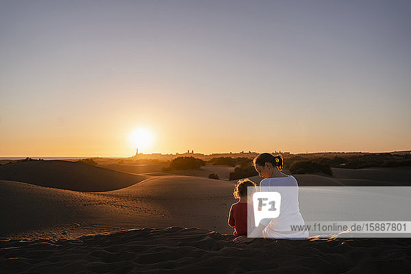 Mutter und Tochter sitzen bei Sonnenuntergang in Sanddünen  Gran Canaria  Spanien