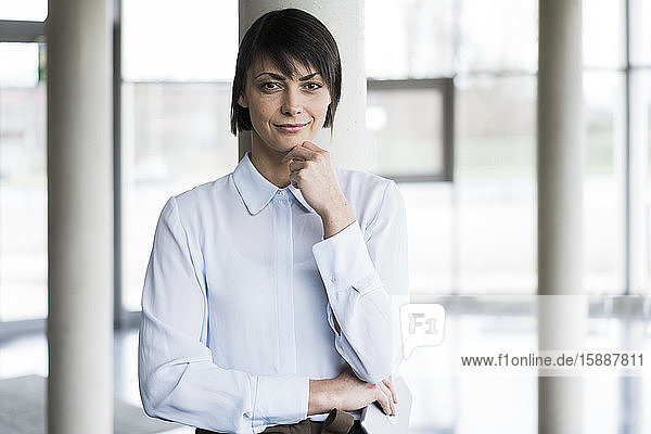 Serene businesswoman standing in bright office building