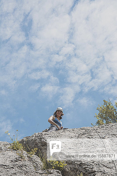 Weibliche Bergsteigerin an Felswand stehend