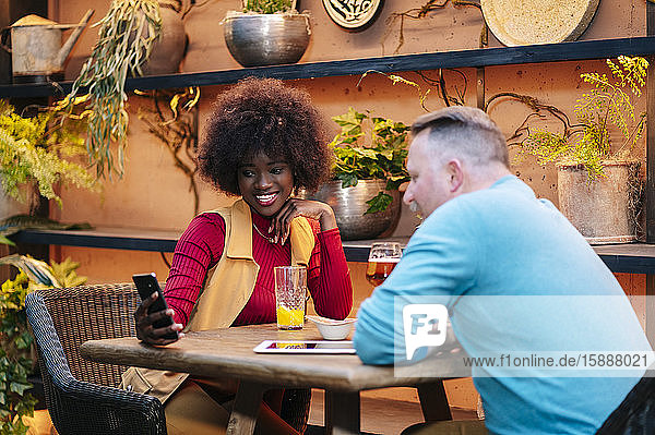 Mann und Frau trinken in einem Restaurant und benutzen ein Smartphone