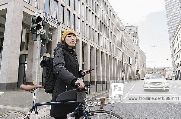 Frau mit Fahrrad und Smartphone in der Stadt  Frankfurt  Deutschland