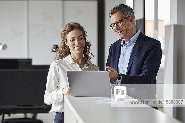 Smiling businessman and businesswoman working together on laptop in office