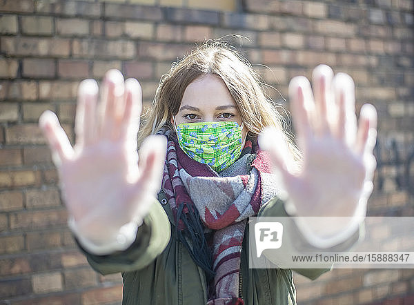 Porträt einer jungen Frau mit Maske  die ihre Hände hebt