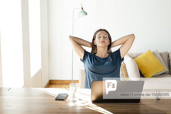 Junge Frau zu Hause entspannt sich und macht eine Pause von der Arbeit am Laptop im Home-Office