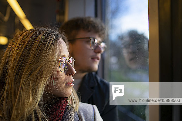 Nachdenkliche junge Frau  die mit ihrem Freund in der Straßenbahn sitzt und aus dem Fenster schaut