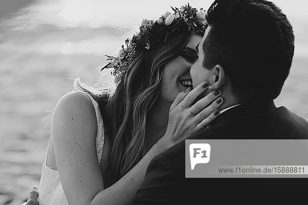 Glückliches Brautpaar küsst sich am Strand  schwarz-weiß