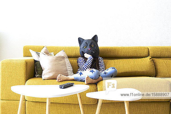 Bored girl sitting on couch  wearing cat mask