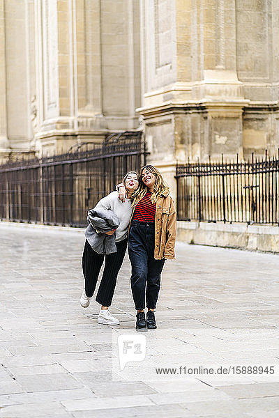 Two happy young women walking in the city