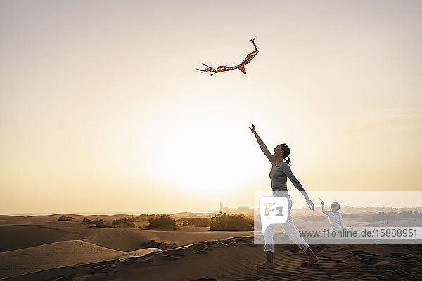 Mutter und Tochter fliegen Drachen in Sanddünen bei Sonnenuntergang  Gran Canaria  Spanien