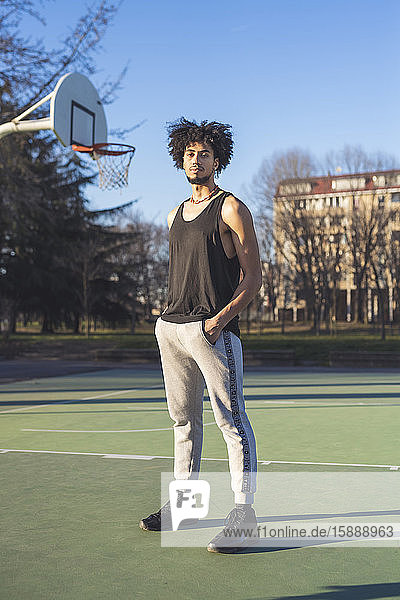 Porträt eines jungen Mannes auf dem Basketballplatz stehend