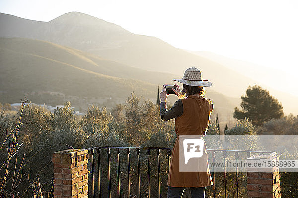Frau macht ein Handyfoto vom Sonnenuntergang auf dem Land  Orgiva  Andalusien  Spanien