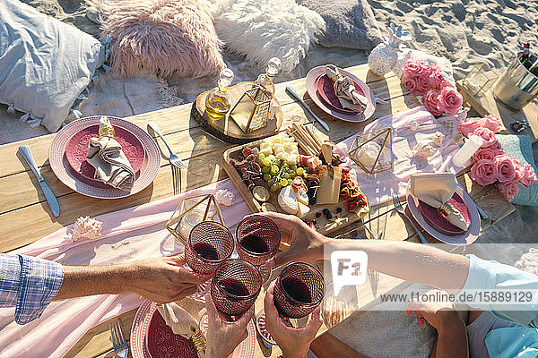 Hände von Freunden stoßen auf Weingläser an  während sie an einem sonnigen Tag ein Picknick am Strand genießen  Riviera Nayarit  Mexiko