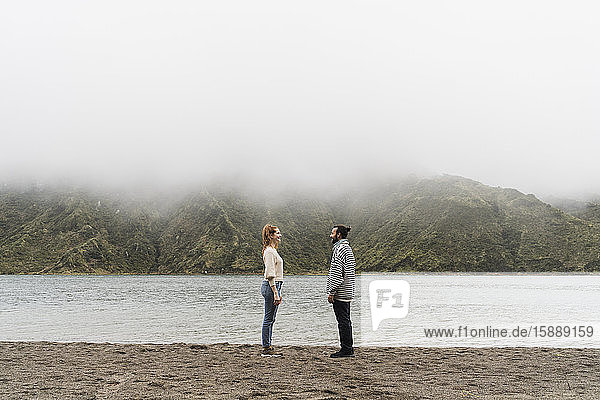 Happy couple standing face to face at lakeshore in Sao Miguel Island  Azores  Portugal